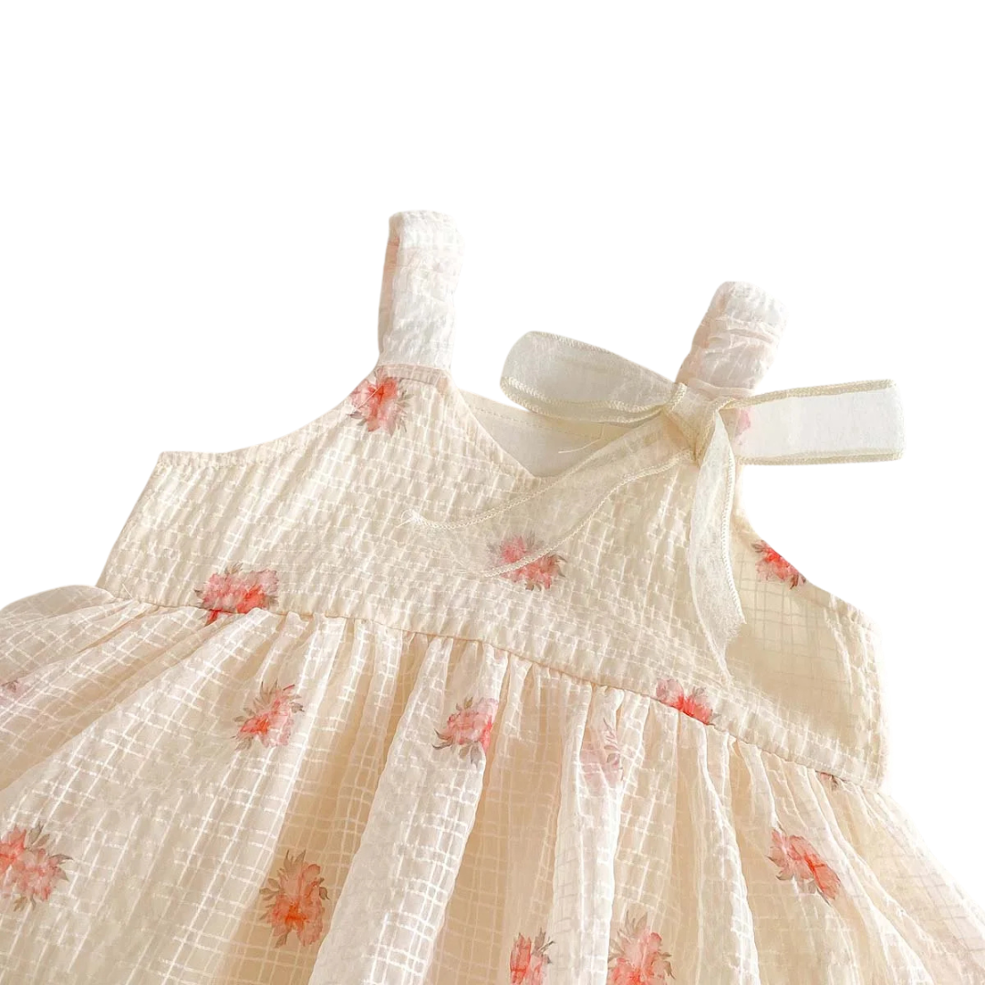Close-up detail of the ruffled bodice and fixed ribbon bow shoulder strap on the floral chiffon baby sunsuit.