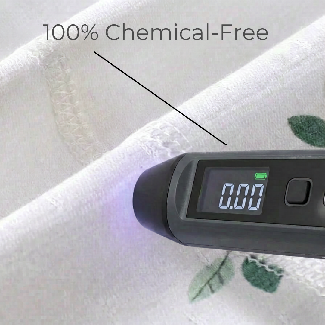 A digital testing device placed against the white cotton fabric displaying a zero point zero zero reading to guarantee one hundred percent chemical-free material.