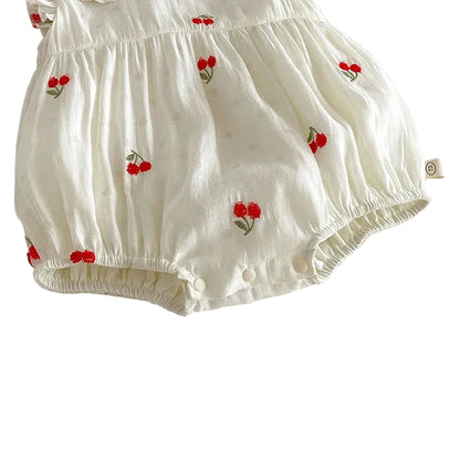 Close-up of the functional bottom snap closures on a cherry embroidered baby romper for easy diaper changes.