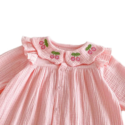 Close up of the sweet cherry embroidery and ruffle Peter Pan collar on the front of the Kidsely pink baby romper.