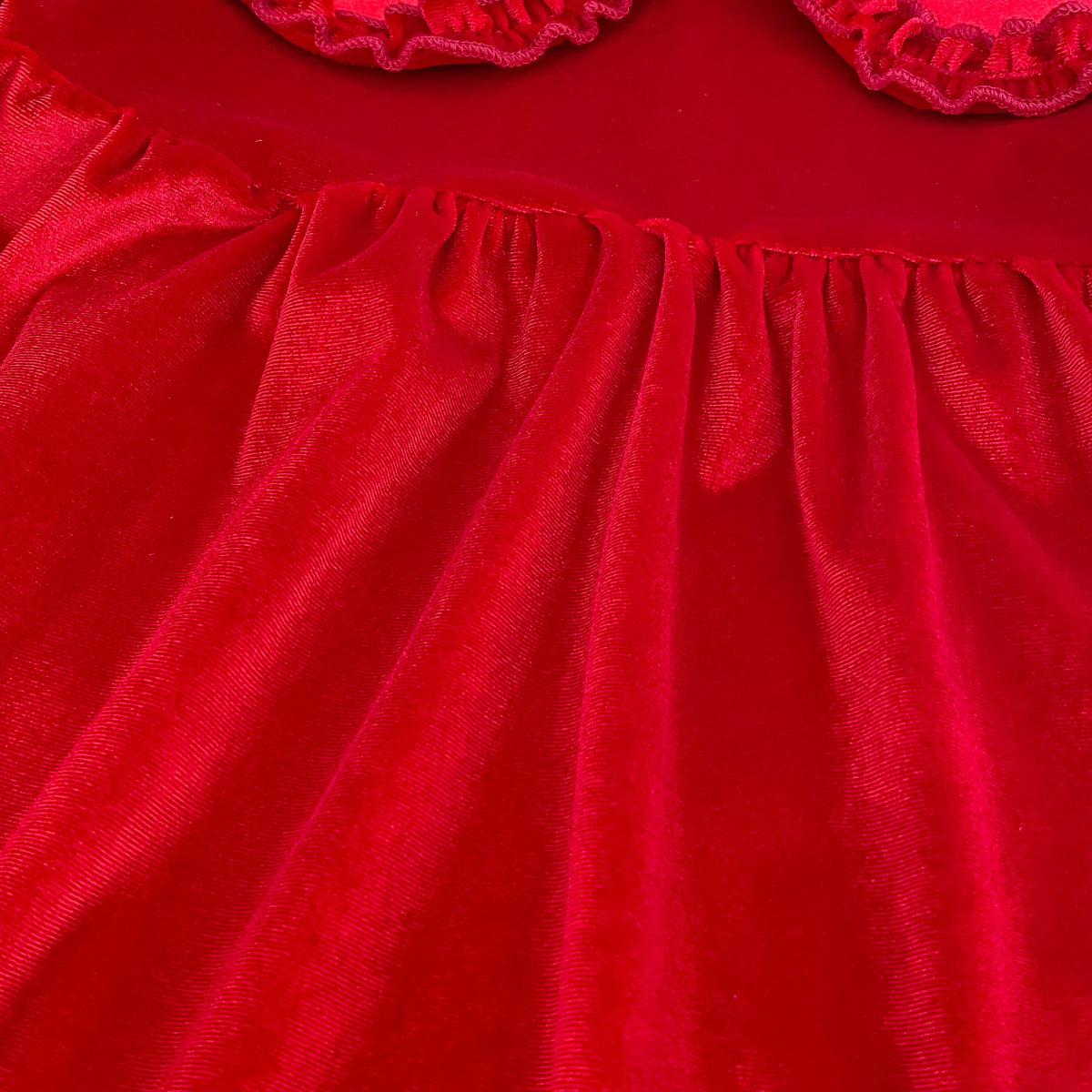 Detail of soft plush cherry red velvet fabric texture and gathered waist styling