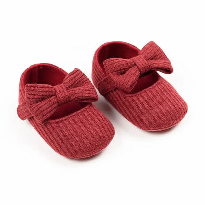Pair of classic red ribbed knit Mary Jane crib shoes with front bows.