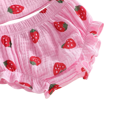 Close-up detail of the breathable 95% cotton crinkle gauze fabric and red strawberry berry print on pink and cream material.