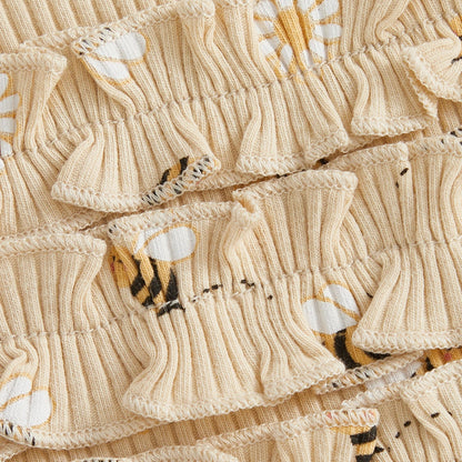 Close-up of the beige ribbed cotton blend fabric showing the bumblebee and daisy pattern and sweet ruffle butt detailing.