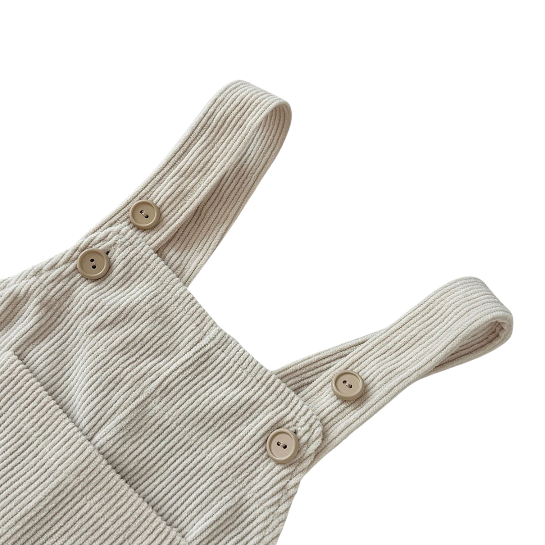 Close-up detail of the adjustable button straps and ribbed corduroy fabric on Kidsely neutral baby overalls.