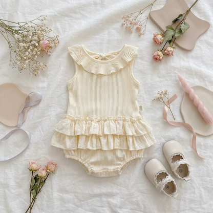 Lifestyle flat lay of the cream pointelle ruffle set paired with vintage baby shoes, dried flowers, and aesthetic candles, ideal for baby photography.