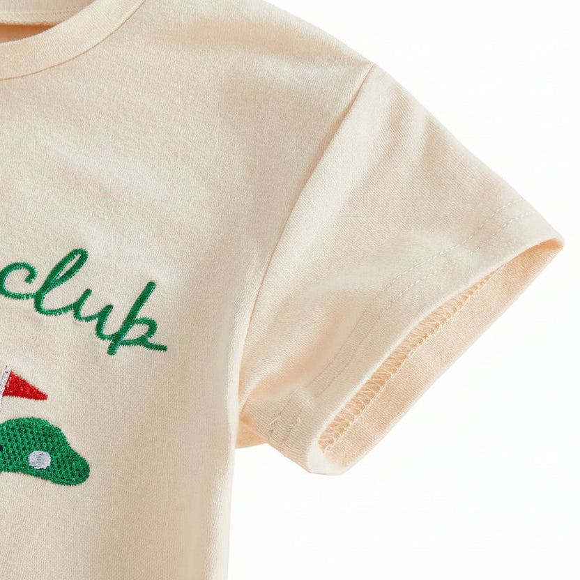 Close-up detail of the short sleeve stitching and soft cotton fabric on the cream baby golf outfit.
