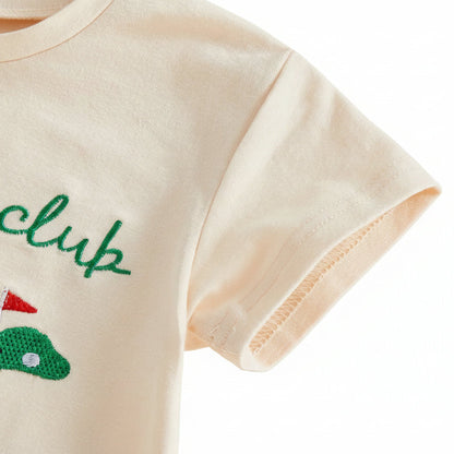 Close-up detail of the short sleeve stitching and soft cotton fabric on the cream baby golf outfit.