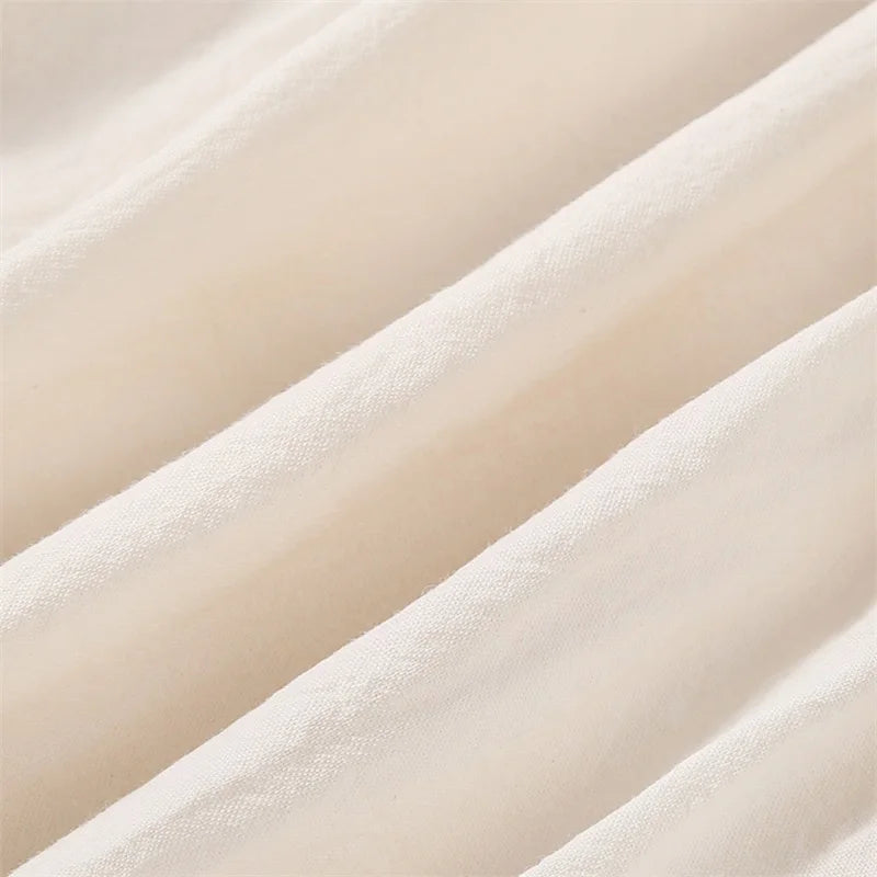 Macro view of the soft, breathable beige cotton-blend woven fabric folds used for the infant clothing.
