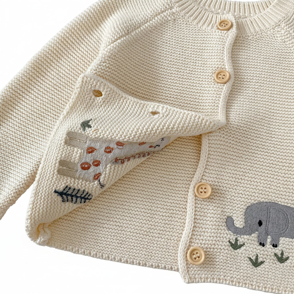 Close-up showing the soft inside lining, neat stitching of the animal embroidery, and button closures of the cream baby cardigan sweater.