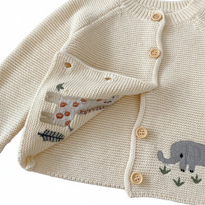 Close-up showing the soft inside lining, neat stitching of the animal embroidery, and button closures of the cream baby cardigan sweater.