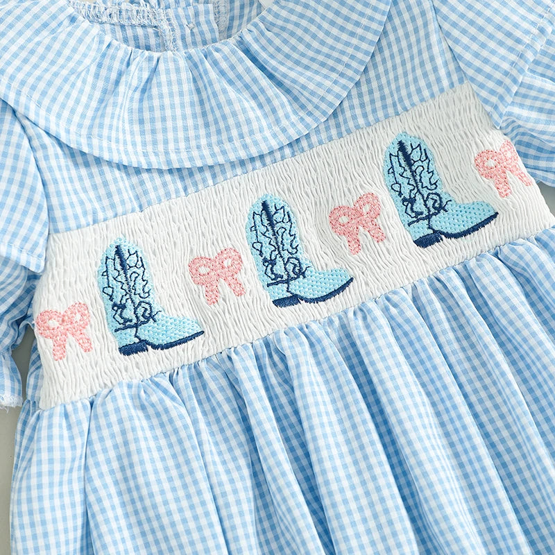 Close up of the detailed chest smocking featuring embroidered blue cowgirl boots and pink bows.