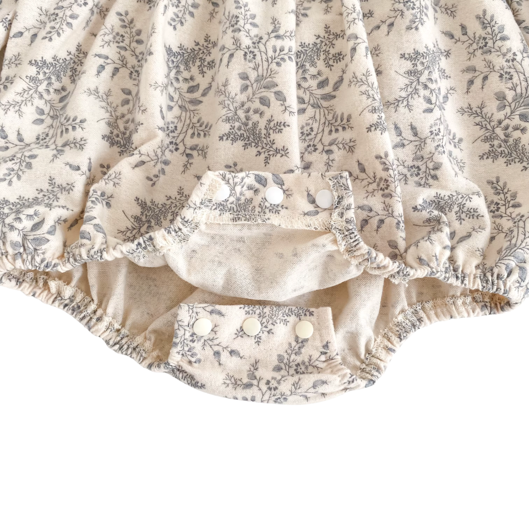 Close-up of the unbuttoned crotch snaps on the bottom of the cream and gray floral bubble romper.