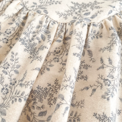 Close-up of the cream and gray botanical floral fabric pattern and shoulder seam on the baby romper.