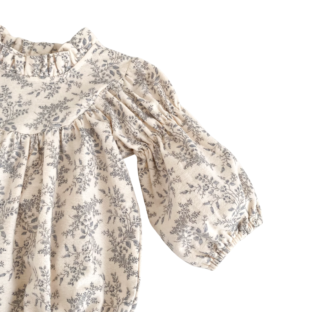 Close-up of the long puff sleeve and elastic cuff on the cream and gray floral baby romper.