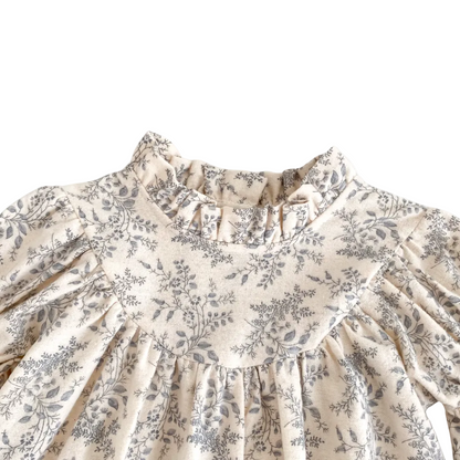 Close-up of the ruffled collar and pleated chest detail on the cream and gray floral baby romper.