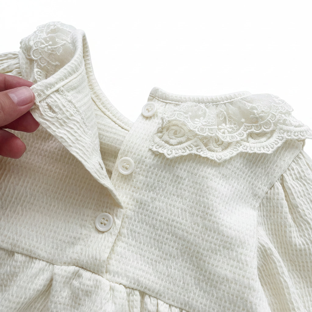 Close-up of the back neck button opening on the cream waffle knit baby girl romper.