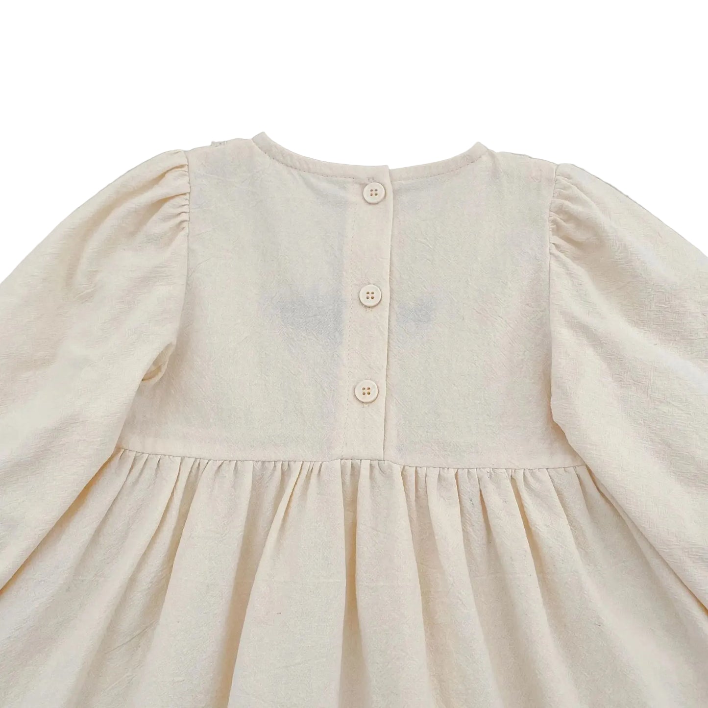 Close-up of the upper back section of the cream baby girl romper showing the three button closures.