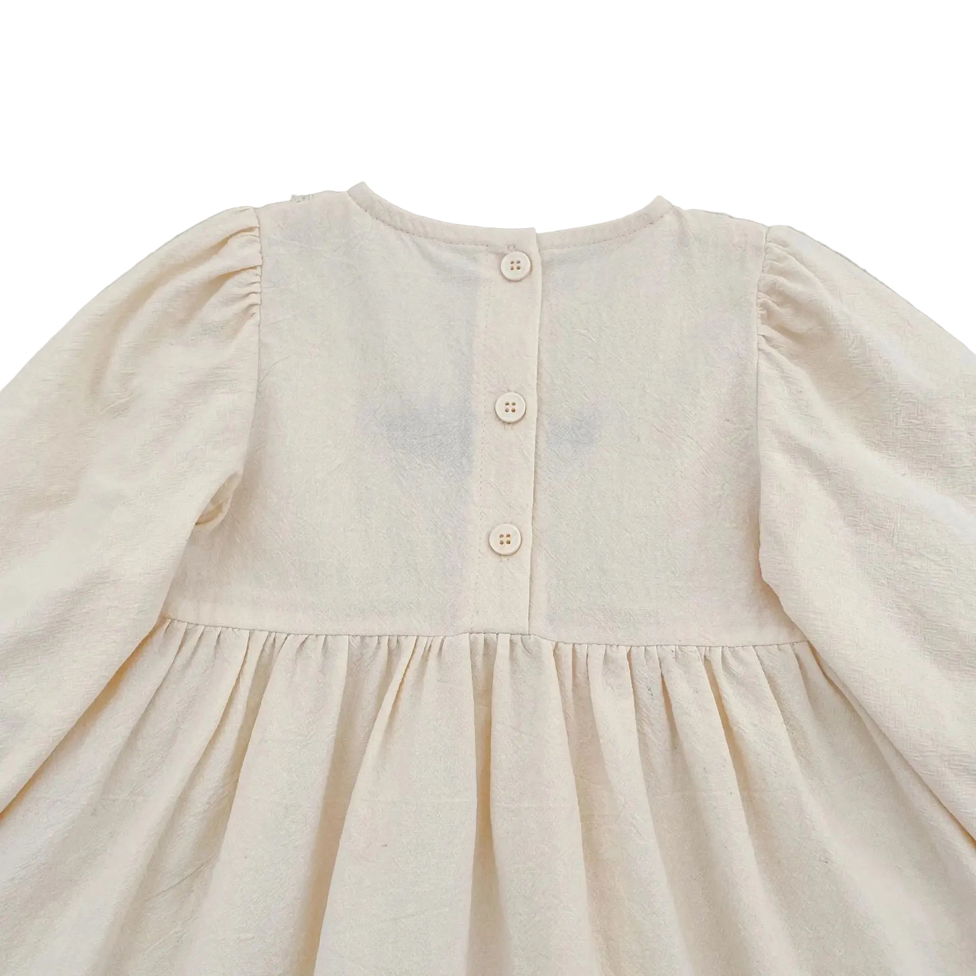 Close-up of the upper back section of the cream baby girl romper showing the three button closures.