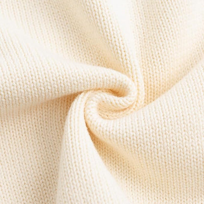 Close up texture detail of the soft, breathable cream cotton knit fabric used for the baby cardigan.