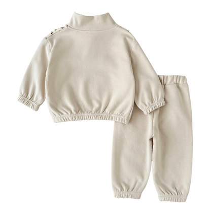Back view of the baby and toddler girls cream sweatshirt and jogger set laid flat on a white background, showing the solid cream back.