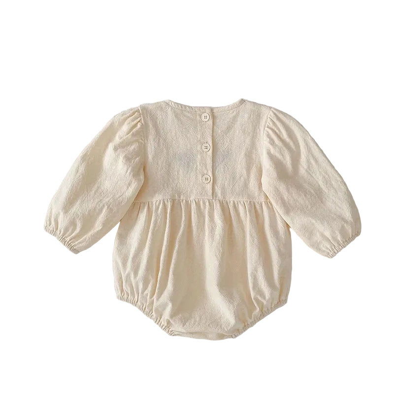Full back view of the cream long sleeve baby girl bubble romper showing the gathered elastic leg openings and back button closures.