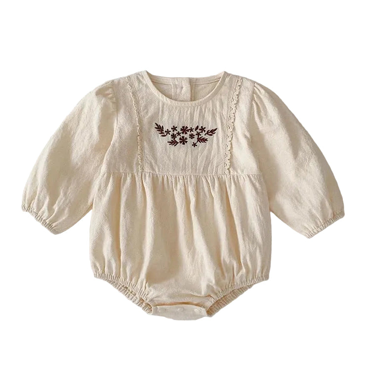 Front view of a vintage-inspired cream long sleeve baby girl bubble romper featuring brown floral embroidery and lace trim on the chest.