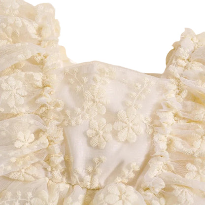 Close-up of square neckline and intricate floral lace embroidery on cream baby dress bodice