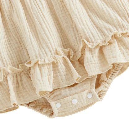 Close-up showing the convenient bottom snap closure and delicate skirted ruffle trim on the cream goose baby romper.