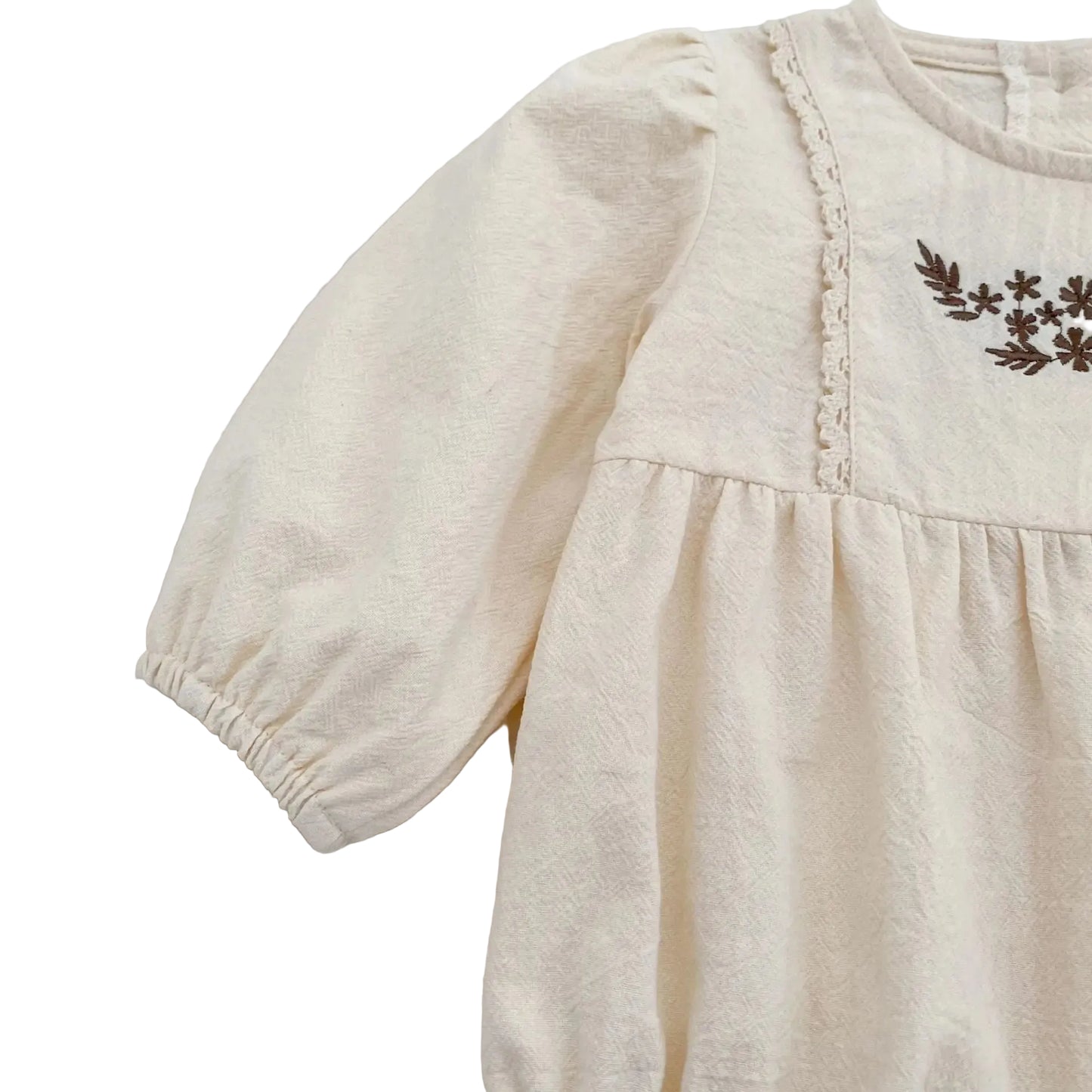 Close-up of the long sleeve and shoulder seam on the cream breathable cotton baby girl romper.