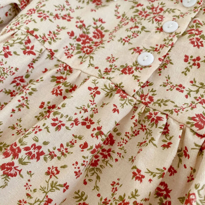 Close-up of the cream and red ditsy floral fabric and functional white front buttons on the baby girl vintage-inspired romper and dress.