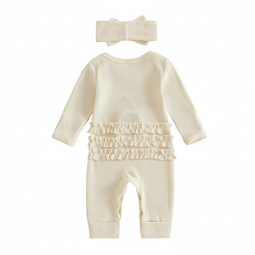 Close-up of the matching cream ribbed pre-tied bow headband and the neckline of the romper showing a size tag.