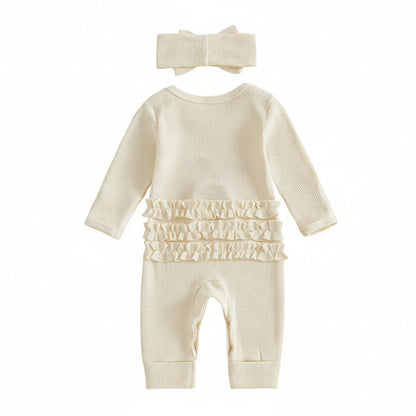 Close-up of the matching cream ribbed pre-tied bow headband and the neckline of the romper showing a size tag.