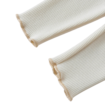 Close-up detail of the lettuce-edge ruffled ankle cuffs on the cream ribbed toddler leggings.