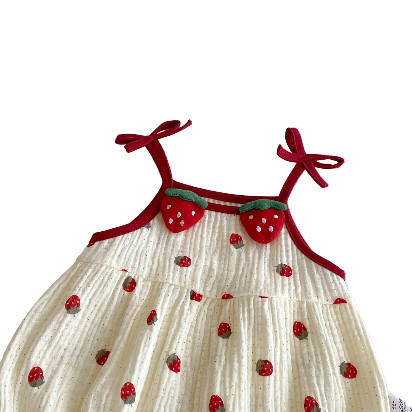 Close-up of the upper chest on the cream baby romper, showcasing the red tie-up shoulder straps and plush 3D strawberry appliques.