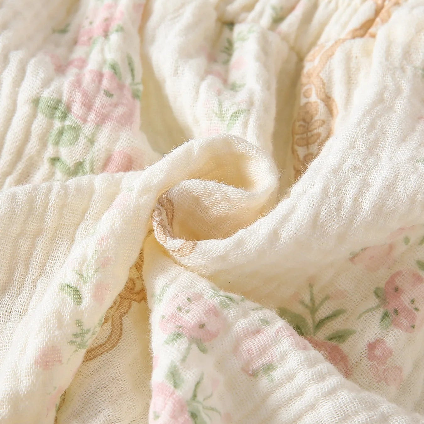 Close-up showing the soft, crinkled texture of the breathable cotton gauze muslin fabric featuring a faded pink vintage floral print.
