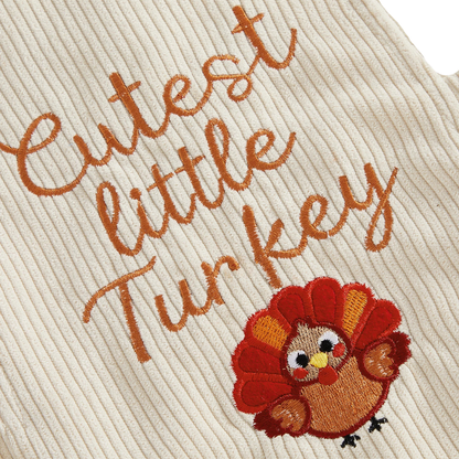 Close-up detail of the brown "Cutest little Turkey" text and turkey embroidery on the beige baby corduroy romper.