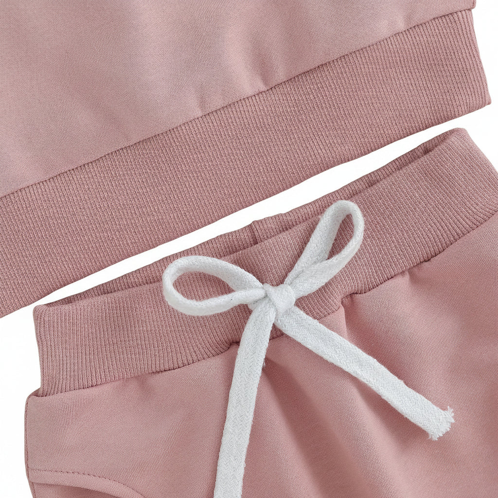 Close-up of the comfortable elastic waistband featuring a decorative white drawstring on the pink baby sweatpants.