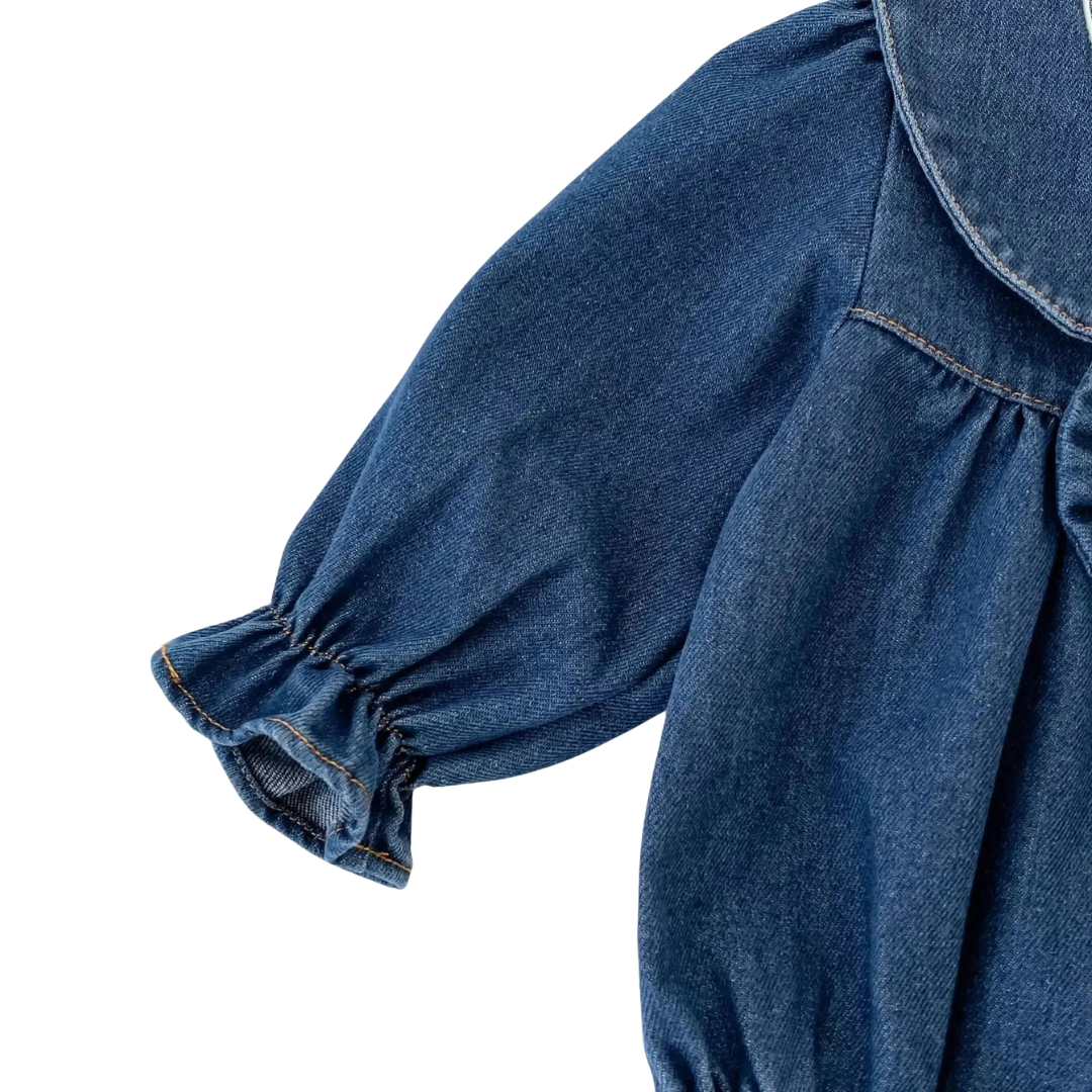 Detailed view of long sleeve with elastic ruffle cuff on dark blue baby denim romper