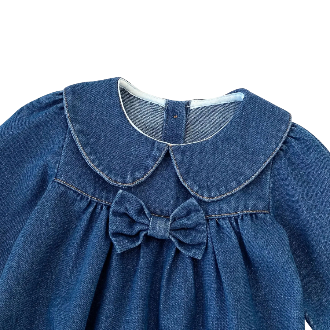 Close-up of Peter Pan collar and chest bow accent on dark blue baby denim romper