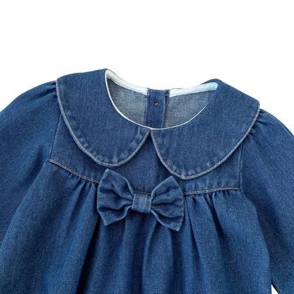 Close-up of Peter Pan collar and chest bow accent on dark blue baby denim romper