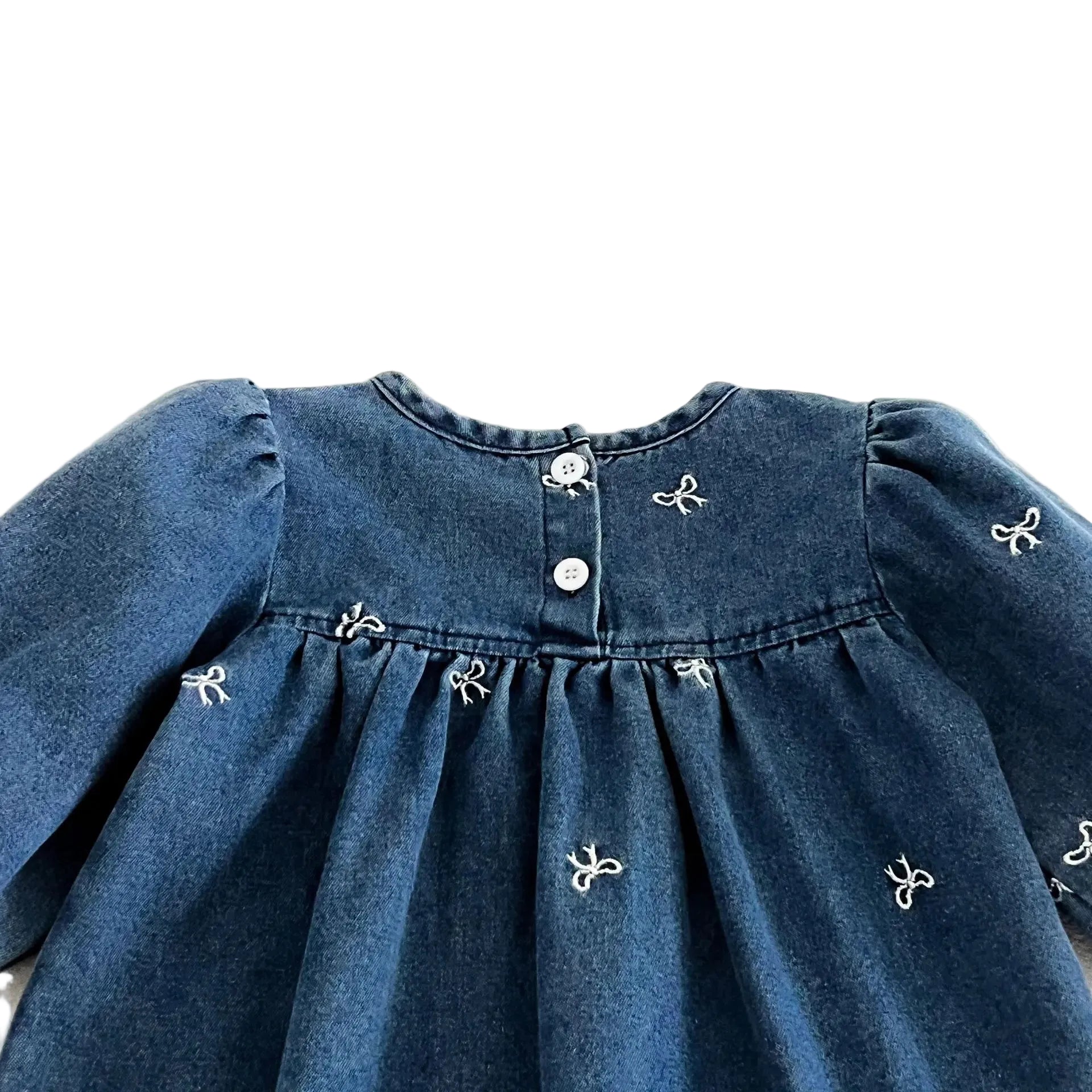 Close up of the back neckline showing the single button loop closure on the blue denim toddler dress.