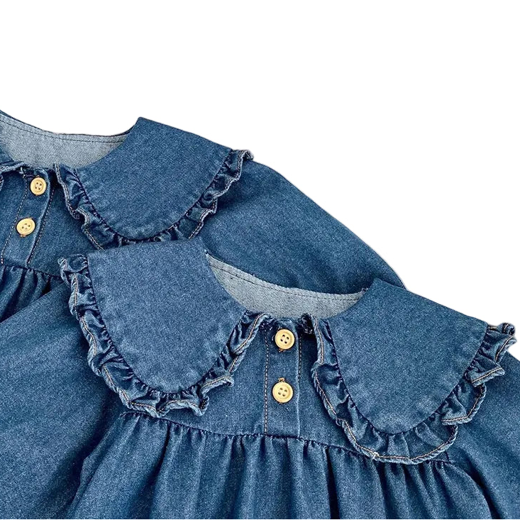 Close-up detail of the vintage-inspired ruffle Peter Pan collar and faux-wood buttons on the baby girl denim romper and dress.