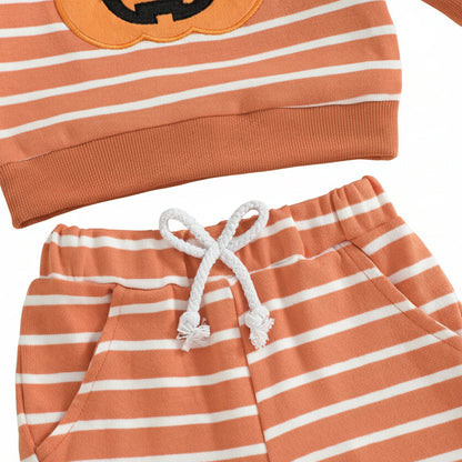 Close-up of the toddler jogger pants showing the elastic waistband, decorative white drawstring tied in a bow, and side pockets on the orange and white striped fabric.