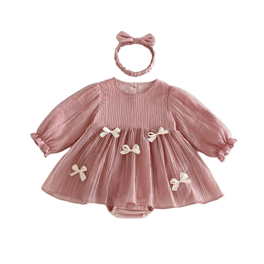 Baby girl dusty pink long sleeve pleated romper dress and matching headband set laid flat against a white background.