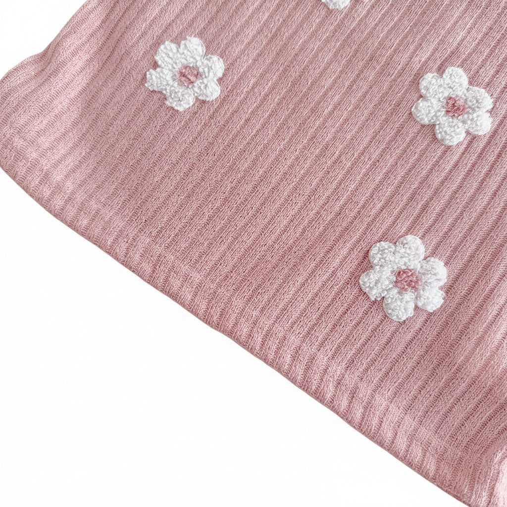 Zoomed-in macro shot of the textured ribbed knit fabric in dusty rose, highlighting the detailed loops on the white 3D floral embroidery patches.