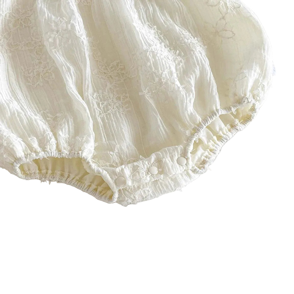 Close-up of the gathered elastic leg openings that create the bubble silhouette on the white baby romper.