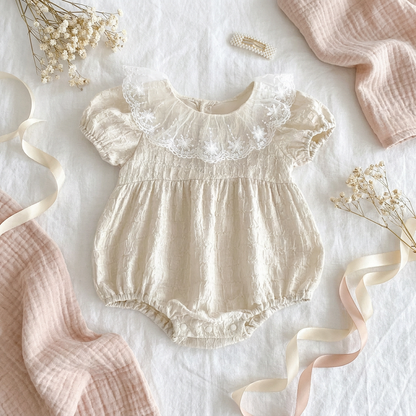 A beautiful aesthetic flat lay of the Heritage Cream baby flower girl romper styled with a soft knit blanket and dried baby's breath flowers.