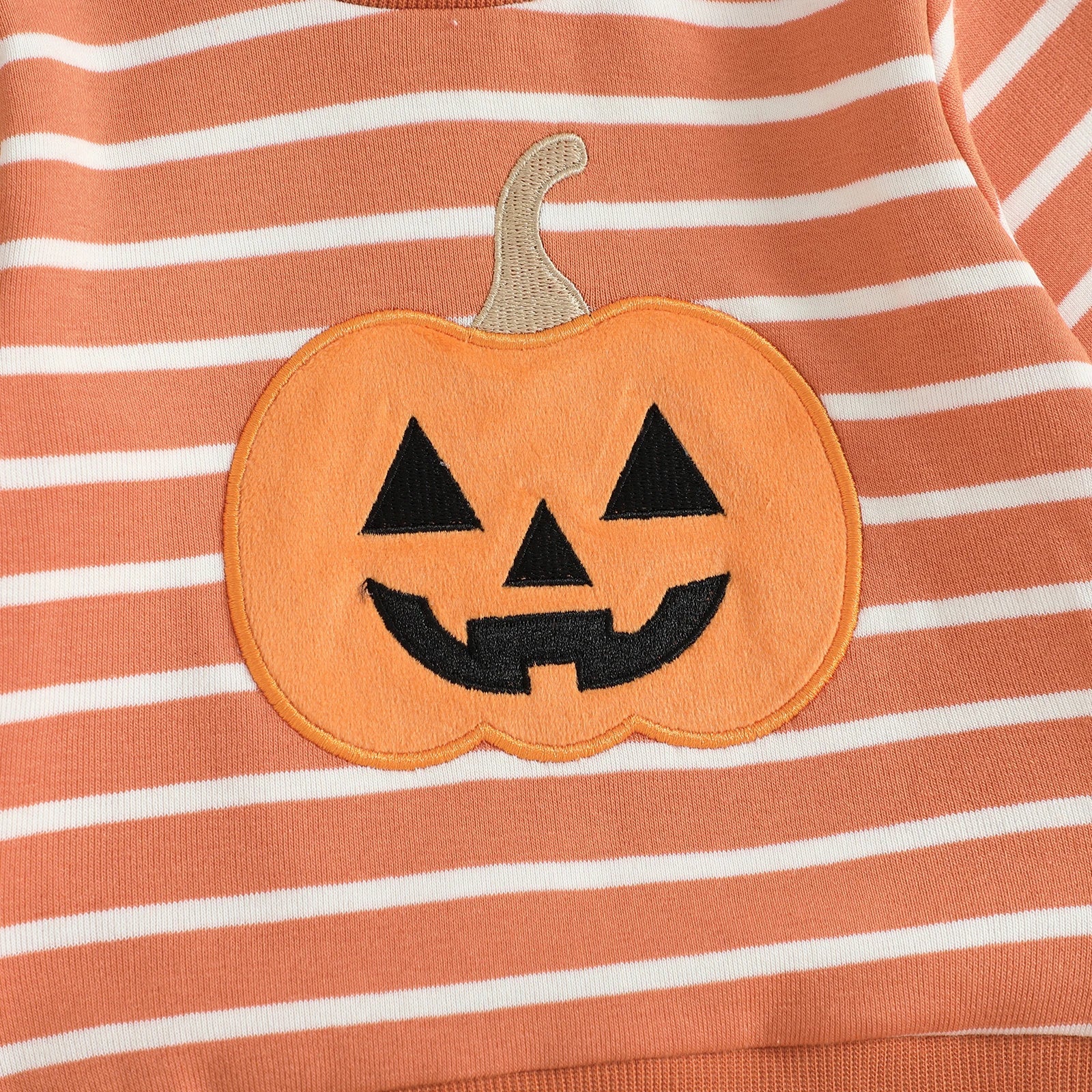 Close-up detail of the high-quality embroidered smiling jack-o'-lantern pumpkin patch on the chest of the orange and white striped toddler sweatshirt.