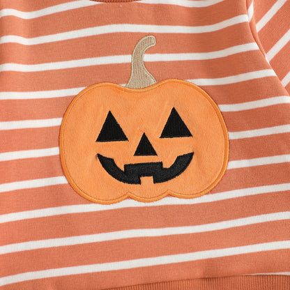 Close-up detail of the high-quality embroidered smiling jack-o'-lantern pumpkin patch on the chest of the orange and white striped toddler sweatshirt.